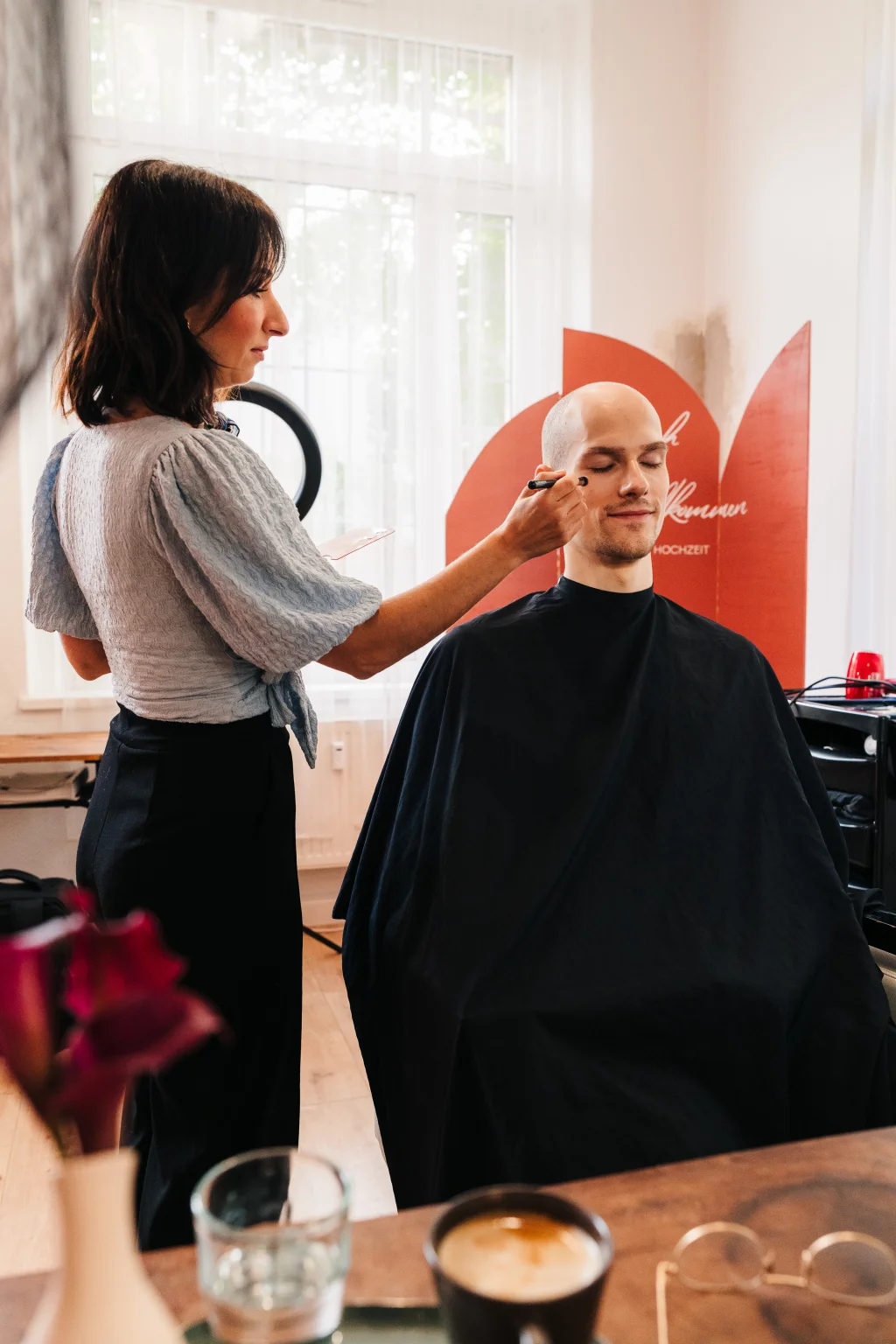 Woman applies makeup to a man’s face